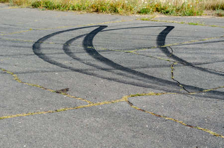 Black traces of car tires on the asphalt. Curved traces of burnt rubber. Car drifting. Motorsport. Outdoor. Selective focus.の写真素材