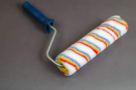 New paint roller on gray background. Hand tool for painting walls, ceilings, furniture and other surfaces. Selective focus.の写真素材