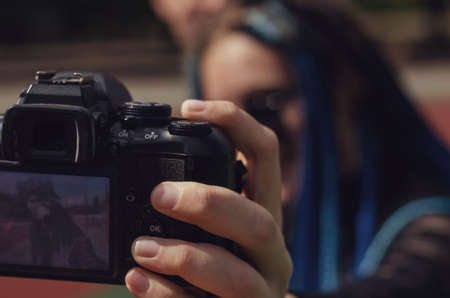 A young woman and a man taking selfies with a DSLR camera. Heterosexual couple in front of the running tracks at the stadium. Female with blue pigtails. Lifestyle. Selective focus.の写真素材