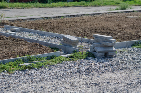 Plotted land parcel. Construction of new walkways. Gray concrete curbs. Sidewalks covered with...