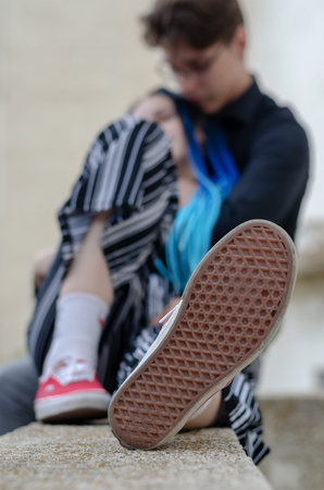 A young man and a woman sitting on a concrete parapet. A heterosexual couple in love. Young Family....