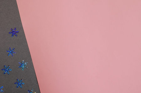 Minimalist composition with shiny Christmas snowflakes on a gray-pink background. Decorative...