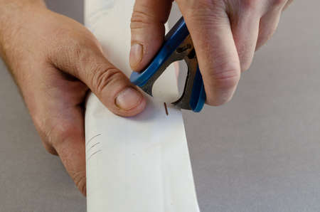 Manager removes staples from documents. Hand holds contract and Staple remover. Clerical device. Close-up. Selective focus.の写真素材