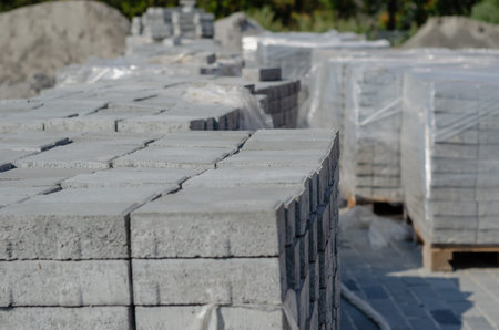 Warehouse of building materials. Lots of Pallets of gray paving tiles. New cement blocks....