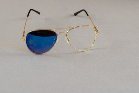 Sunglasses with one glass on gray background. Yellow metal frame of sunglasses with broken glass....