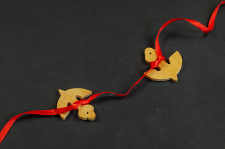 Two wooden anchors tied with red ribbon. Anchor figures on black surface. Nautical theme. Selective...