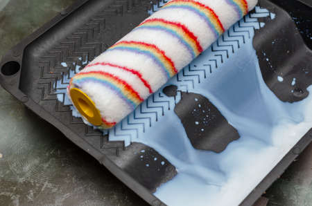 The paint roller is squeezed out in a plastic tray. The wall primer runs off. Painting. Indoors. Selective Focus.の写真素材