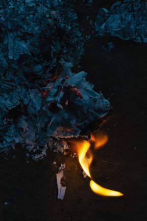 Burned to the ground business diary. Gray ashes from the pages of a notebook. Burned-out sheets of paper outside. Twilight. Defocus, blur, noise, grain effect.の写真素材