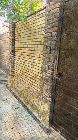 Tall stone fence with brown door. Private property. Digital watercolor painting.の写真素材