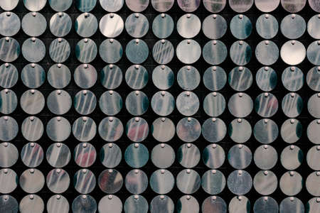 A defocused shot of repeating metallic shiny circles. A multitude of round-shaped objects fluttering in the wind. Blurred motion, selective focus, noise, grain effect.の写真素材