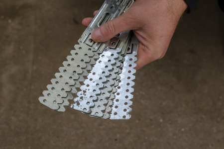 Man holds Long perforated galvanized steel plates. Fixture for the construction of gypsum...