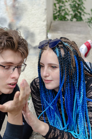Heterosexuals. A happy young family. A woman reads her husband's hand. A female with long blue pigtails lies on a concrete parapet. Love, relationships. Selective focus.の写真素材