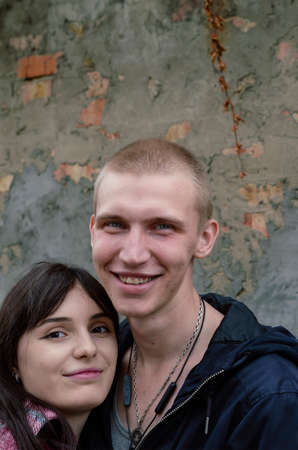 A heterosexual couple in love against a gray wall. A young man with short hair and a woman with long black loose hair. Young family or lovers. Selective focus.の写真素材
