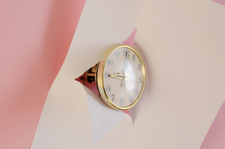 Vintage clock, white tear paper, pink background. Round Mechanical table clock in gilded frame....