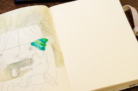 Coloring with a watercolors Pencil drawing of a dog with a cup of coffee. The animal sits in an armchair. Open notebook on brown wooden table. Part of a seriesの写真素材