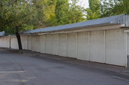Closed Street Market Stores. The market stalls are covered with white metal shutters. Daytime. No...