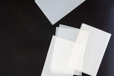Minimalist composition with white plastic sheets. Rectangular textured sheets against a black background. Angled view from above.の写真素材