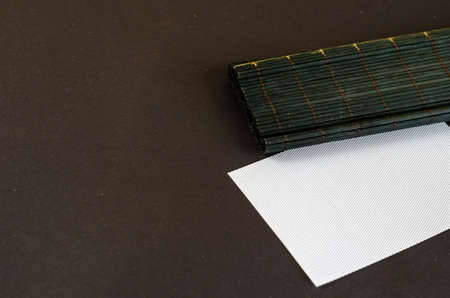 Dark green bamboo table cloth and white rectangle opposite black background. Plastic blank textured card. Selective Focus.の写真素材