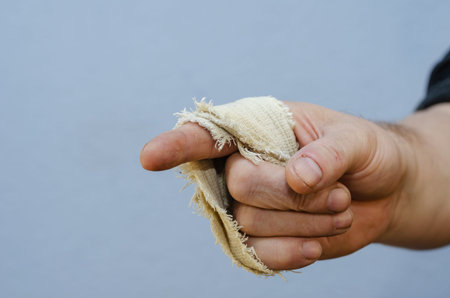 Gesture with index finger. Man's hand wrapped with a narrow strip of cloth. Right hand of adult male against the blue background. Close-up. Selective focus.の写真素材