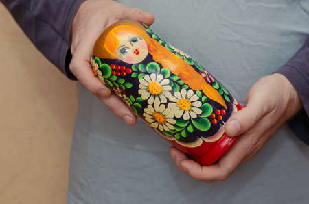 An adult man holding a wooden matryoshka doll. Toy. Symbol of Russia. Selective focus.の写真素材