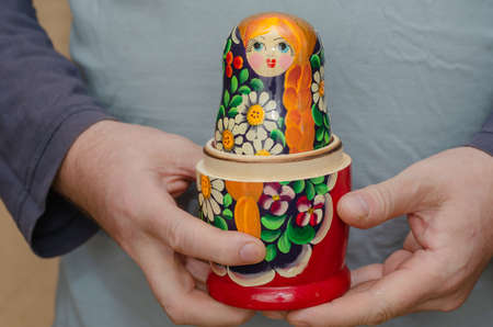An adult male holding a wooden matryoshka doll. An uncovered traditional Russian toy. Symbol of Russia. Selective focus.の写真素材