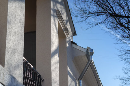 The top of the old white and pink two-story building. Balcony with rectangular columns. A sunny...