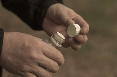Two hands of a grown man holding a plastic bottle. Liquid fire starter. A selective trick.の写真素材