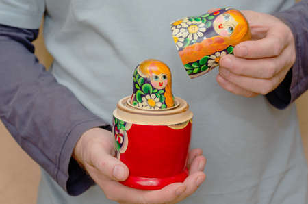 An adult male holding a wooden matryoshka doll. An uncovered traditional Russian toy. Symbol of Russia. Selective focus.の写真素材