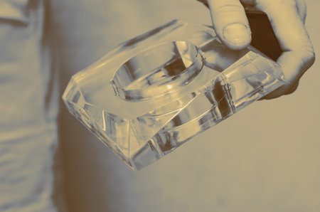 A man holds a glass figure in his hand. Transparent geometric shape. Selective focus.の写真素材