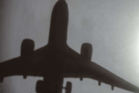 Blur, defocus, noise, grain effect. Dark silhouette of an airplane on a light gray wall. Indoor. Selective focus. No people.の写真素材