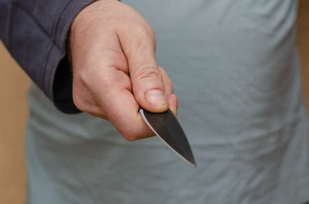 Hand with a knife. Middle section of a man holding a sharp knife. Selective focus.の写真素材
