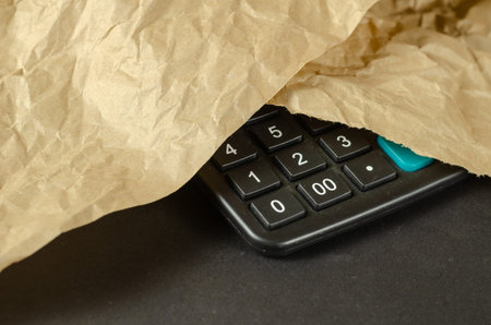 Black calculator covered with wrapping paper. Close-up. Selective focus.