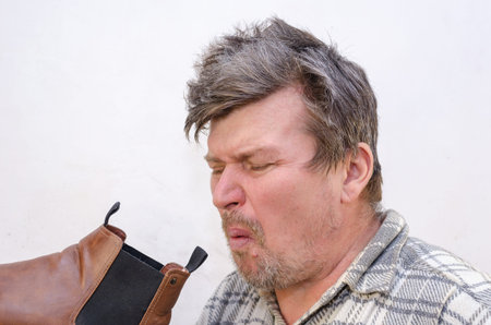 The man smelled an unpleasant odor from his brown boot. A male with disheveled hair against the...
