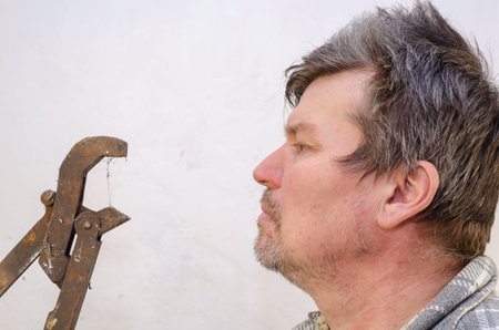 Portrait of a geezer talking with a dusty pipe wrench. Profile of an Unshaven Man and a Rusty Hand...