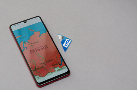 Smartphone and Visa Bank Card Piece against a gray background. A red map of Russia on the smartphone...