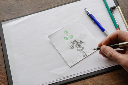 An adult male hand draws a girl with green balloons on paper. Dot drawing with a pen on a white...