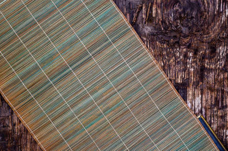Green bamboo napkin on a dark wooden background. Cracked wooden surface with cracks and splinters. top view. selective focus.の写真素材