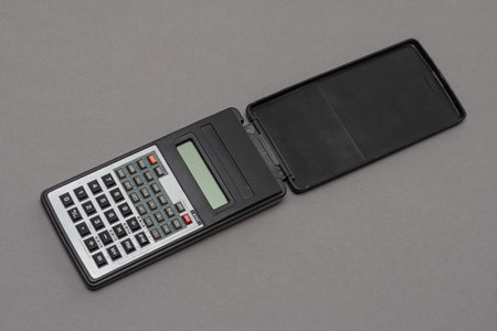 Scientific calculator against gray background. Rectangular device designed for engineering and...