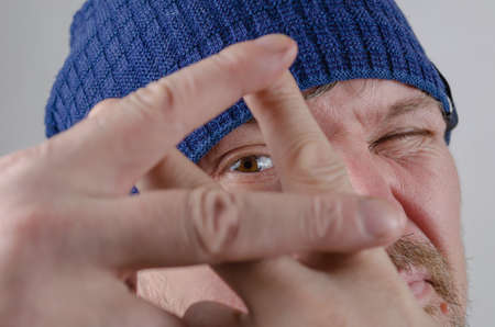 An adult man shows a hashtag gesture in front of his face. A middle-aged male looks through crossed fingers. close-up. selective focus.の写真素材