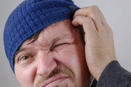 Portrait of an adult male scratching his head with his hand. Pensive funny middle-aged male in a...