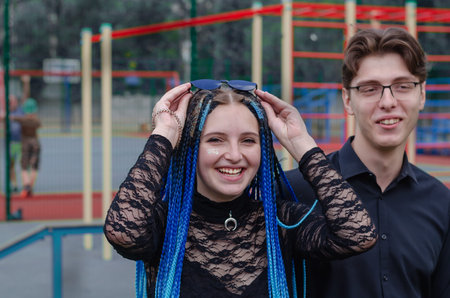 Laughing happy young woman and young man in front of a sports field. Heterosexual couple in love...