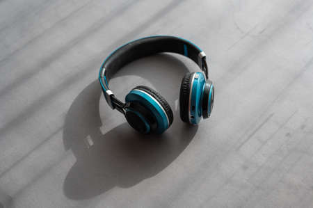 Turquoise and black headphones against a gray background. Wireless device for listening to music and communication.の写真素材