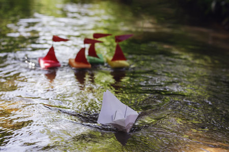 Ships made of kitchen sponges in pursuit of a white paper ship. Children's sailboat regatta....