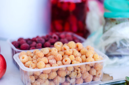 agricultural industry. street trade. traditional fair. Yellow raspberries in a transparent box. Ripe...