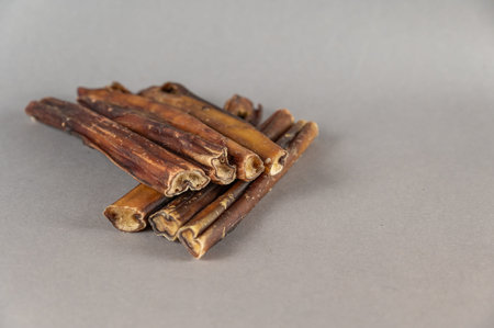 Pet chew treats. Natural dog dried treats against a gray background. Group of bully sticks. pet...