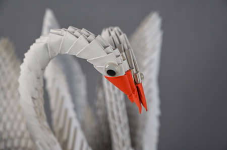 A pair of origami swans against a gray background. Two birds assembled from white triangular pieces of paper. A symbol of family, love, loyalty and devotion. selective focus.の写真素材