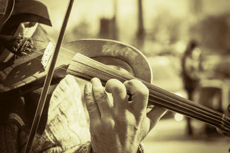 Close-up of a street musician's hands during a concert. Mature man playing electronic violin.の写真素材