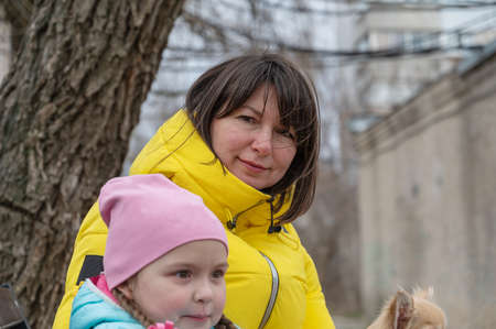 Mothers with a preschool-aged daughter and a pet in their arms outside. A five-year-old girl, a middle-aged woman and a Chihuahua dog. family. close-up.の写真素材