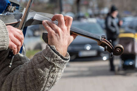 Close-up of a street musician's hands during a concert. Mature man playing electronic violin.の写真素材