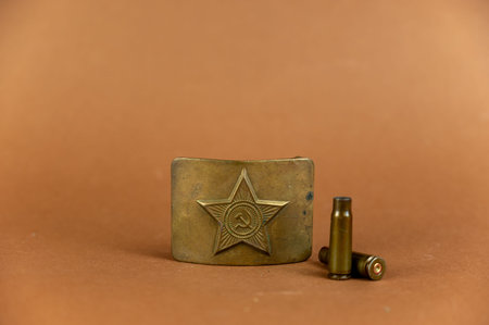 Soviet belt buckle and empty shell casings against brown background. Attribute of the Red Army...